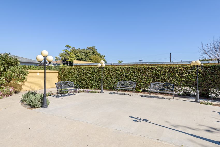 a seating area with benches and lamps in front of a hedge - Photo Gallery