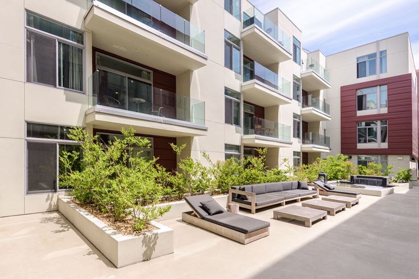 an image of an apartment complex with lounge chairs and trees