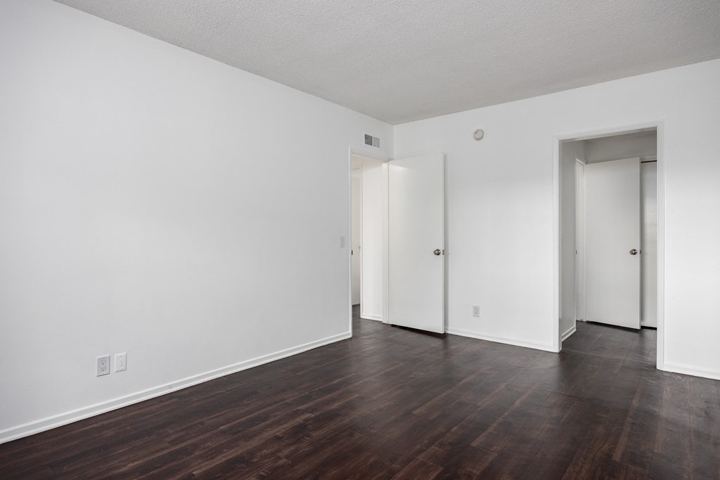 an empty living room with wood floors and white walls