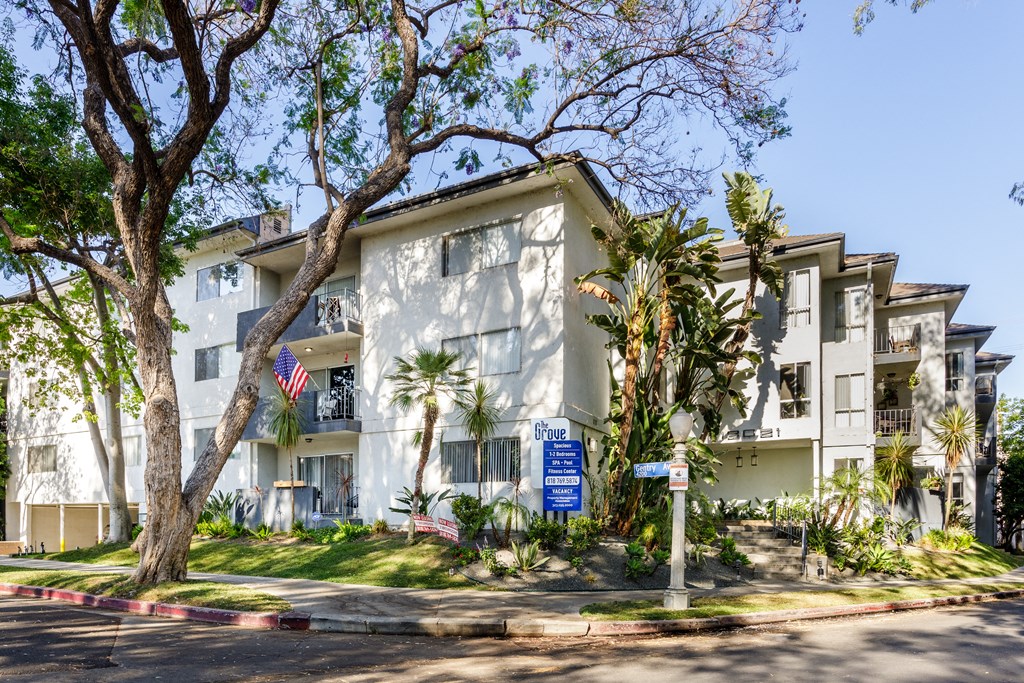 a white apartment building with palm trees and a blue sign