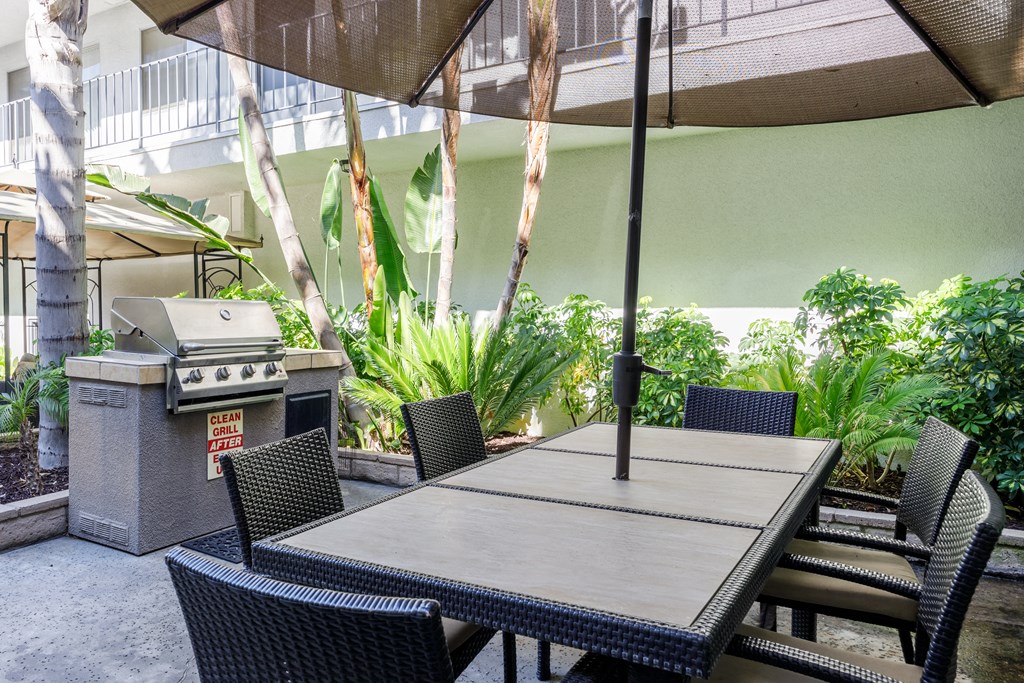 a patio with a table and chairs and a grill