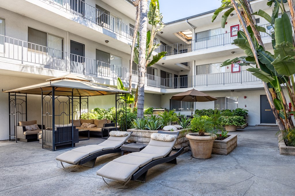 a courtyard with lounge chairs and umbrellas