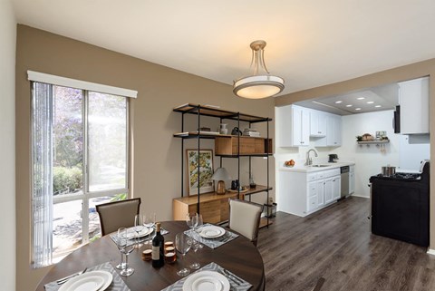 A dining room with a table set for two with a view of a backyard.
