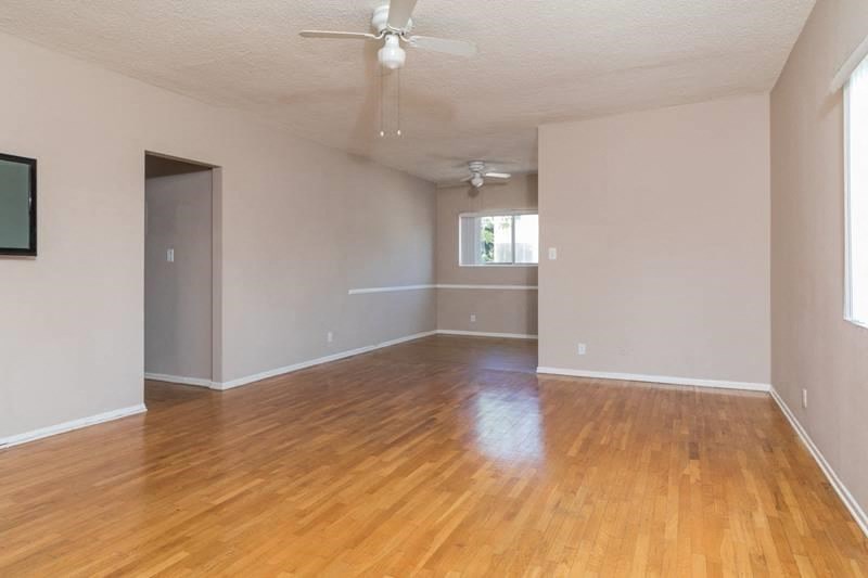 an empty living room with wooden floors and a ceiling fan