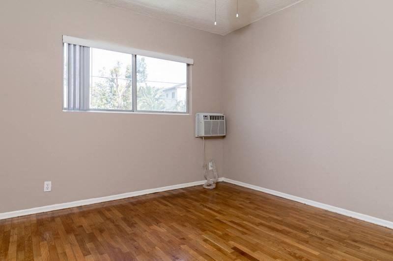 an empty living room with a window and wooden floors