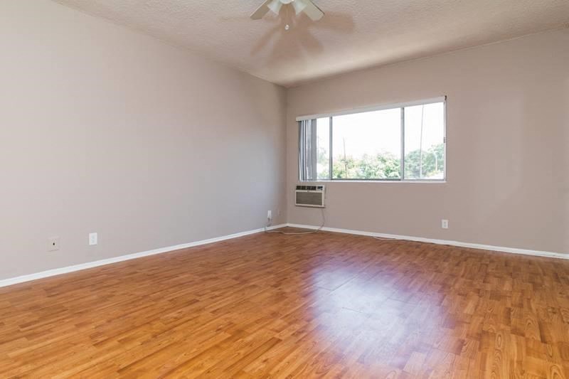an empty living room with wood floors and a window