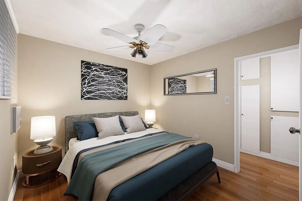 A bedroom with a bed, two lamps, a ceiling fan, and a mirror.