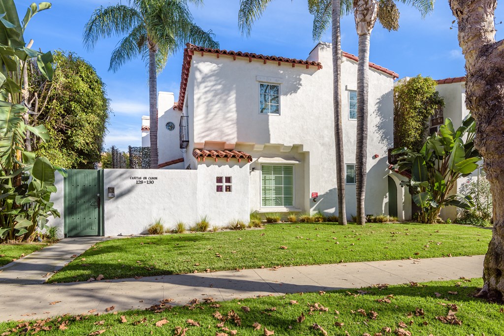 a white house with palm trees and a sidewalk