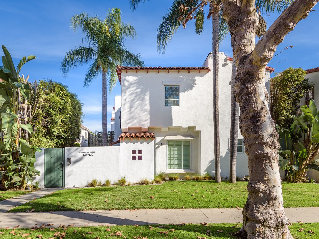 a white house with palm trees and a sidewalk