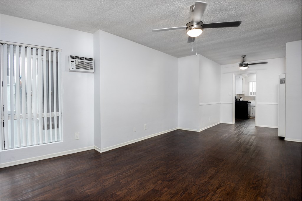 an empty living room with white walls and a ceiling fan