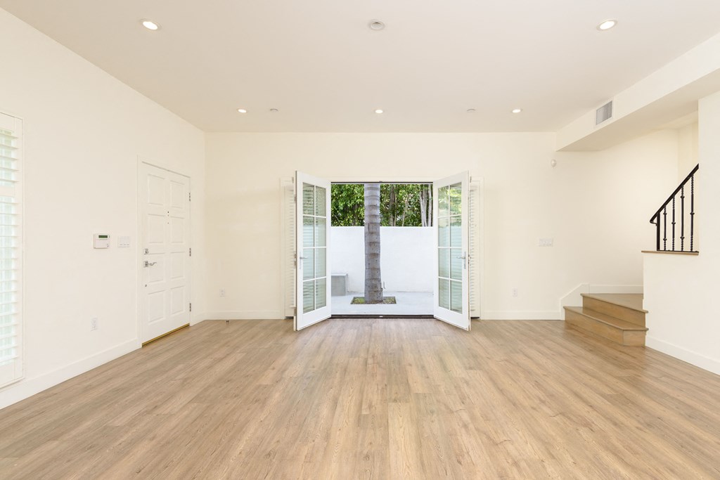 a living room with a hardwood floor and a door to a courtyard
