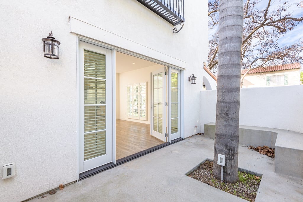 a patio with a tree and a white house