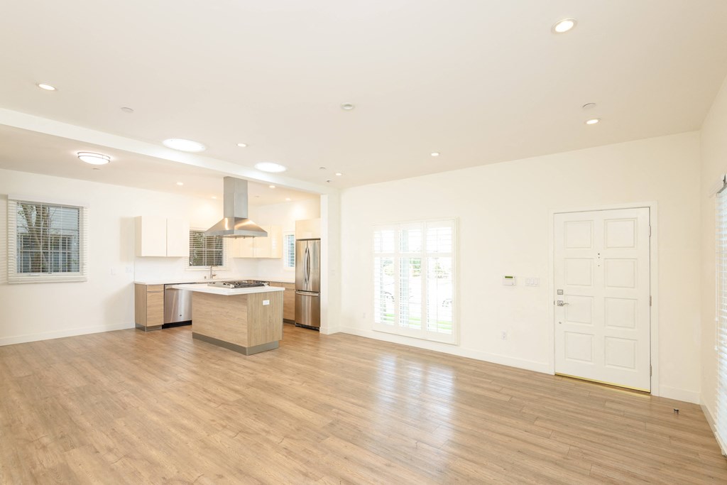 the living room and kitchen of a new home with white walls and wood floors