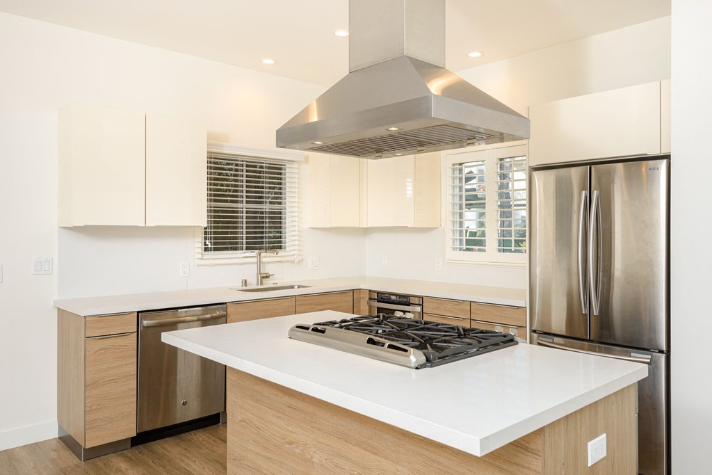 a kitchen with white counter tops and a stainless steel refrigerator