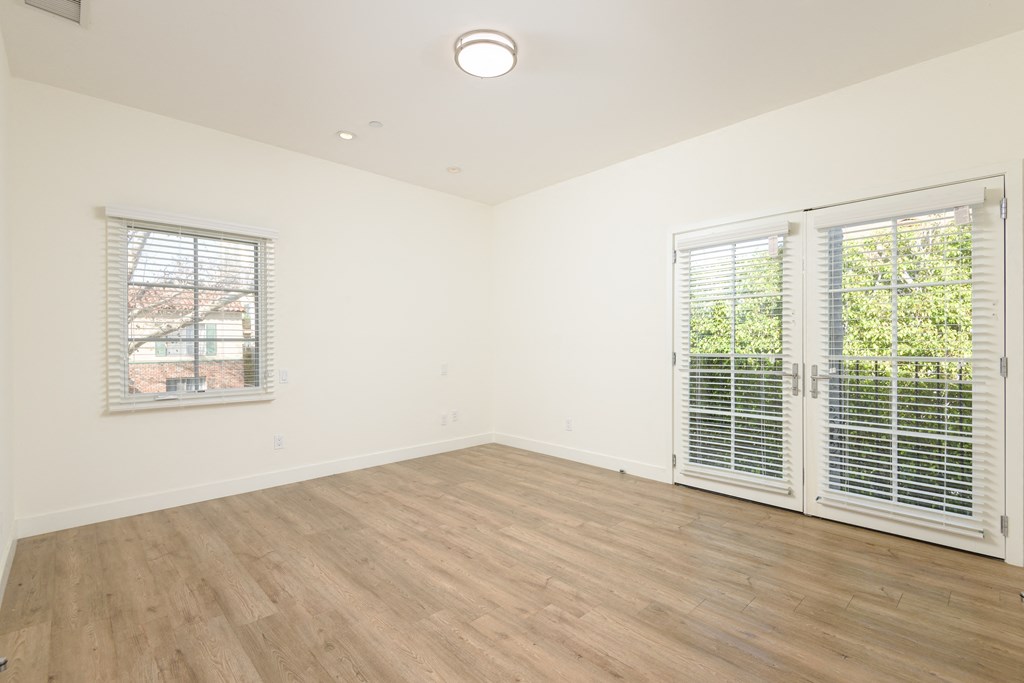 a living room with white walls and wood floors and a window