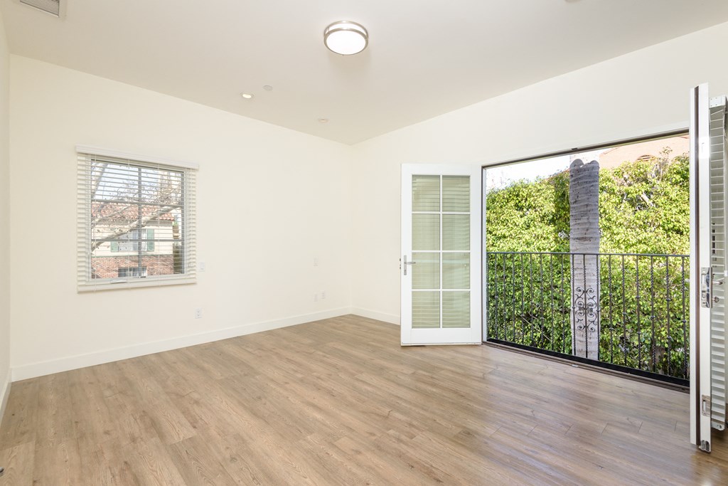 a living room with white walls and a door to a balcony