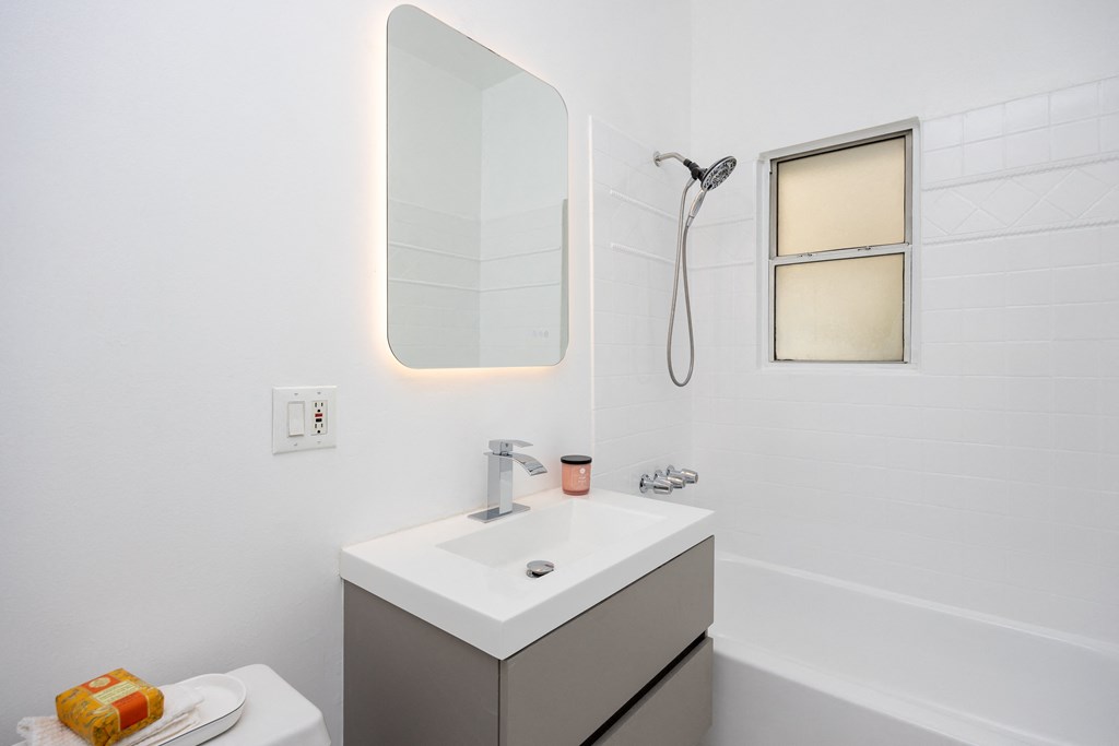 a bathroom with white walls and a white sink with a mirror above it