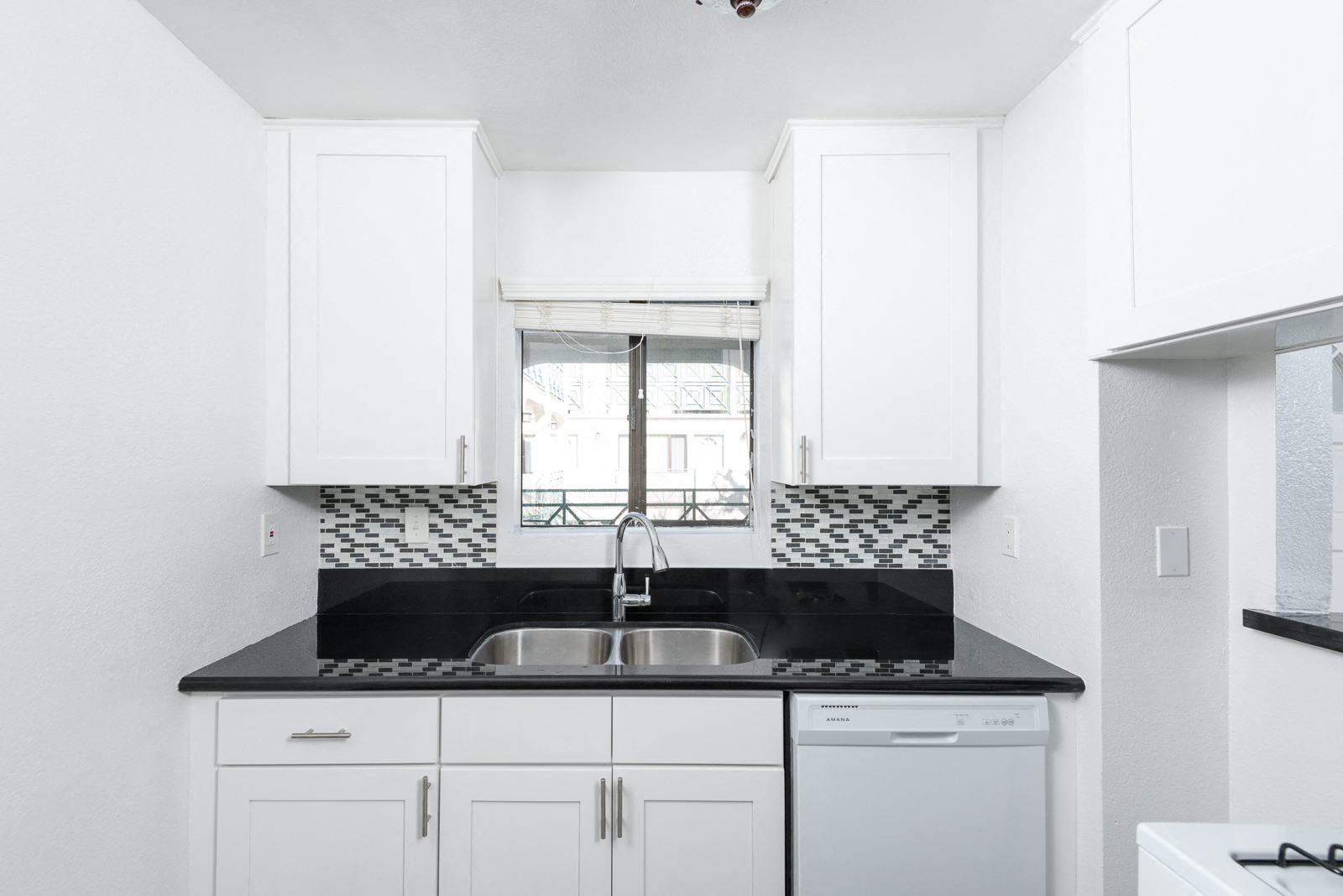 a kitchen with white cabinets and a sink and a window