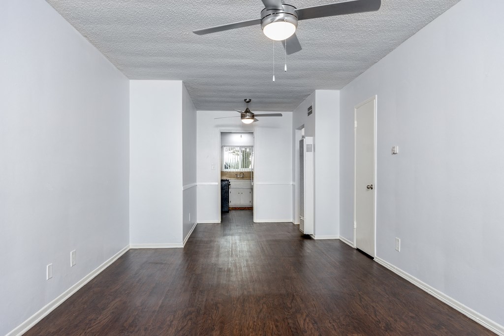 an empty living room with white walls and a ceiling fan