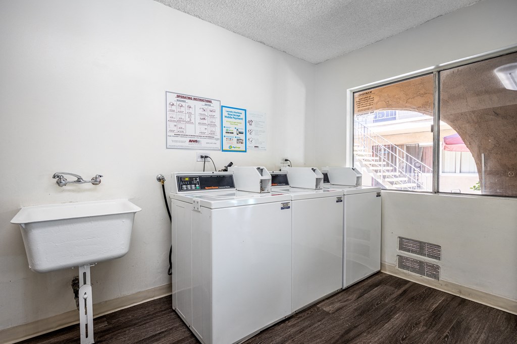 a laundry room with washing machines and a sink and a window