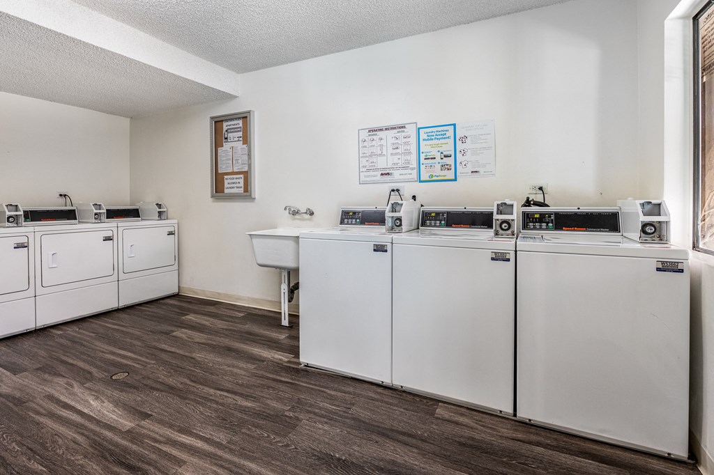 a kitchen with white appliances and a wood floor and white walls