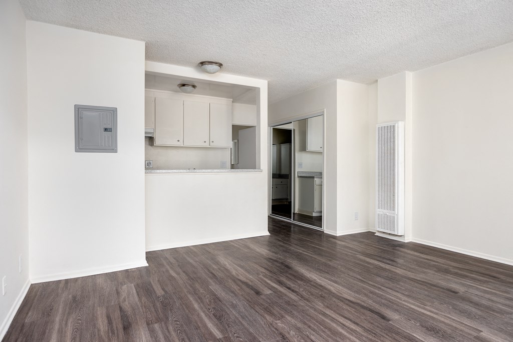 an empty living room and kitchen with white walls and wood flooring
