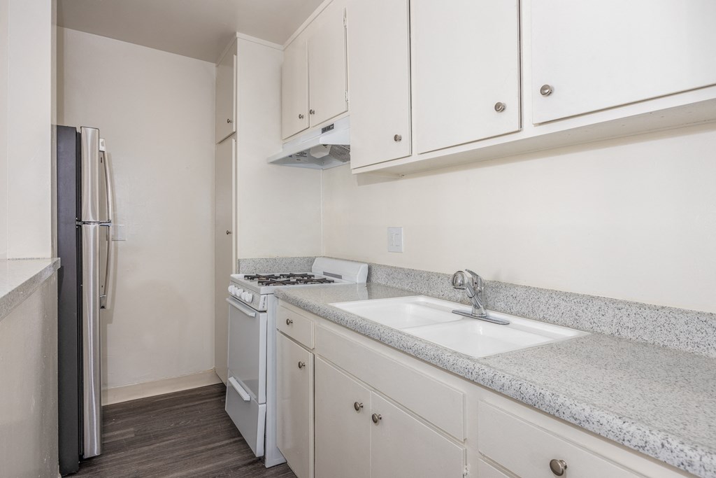 a kitchen with white cabinets and a sink and a refrigerator