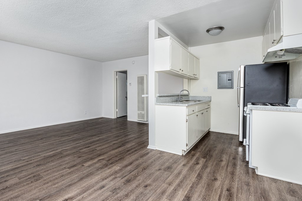 an empty kitchen and living room with a hard wood floor