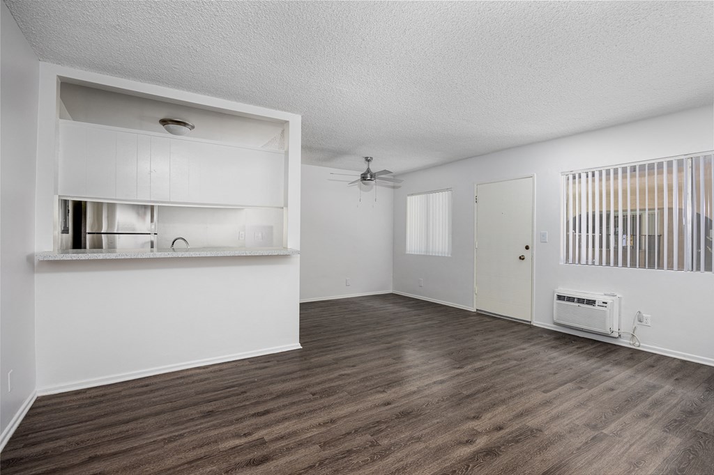 an empty living room and kitchen with white walls and wood flooring