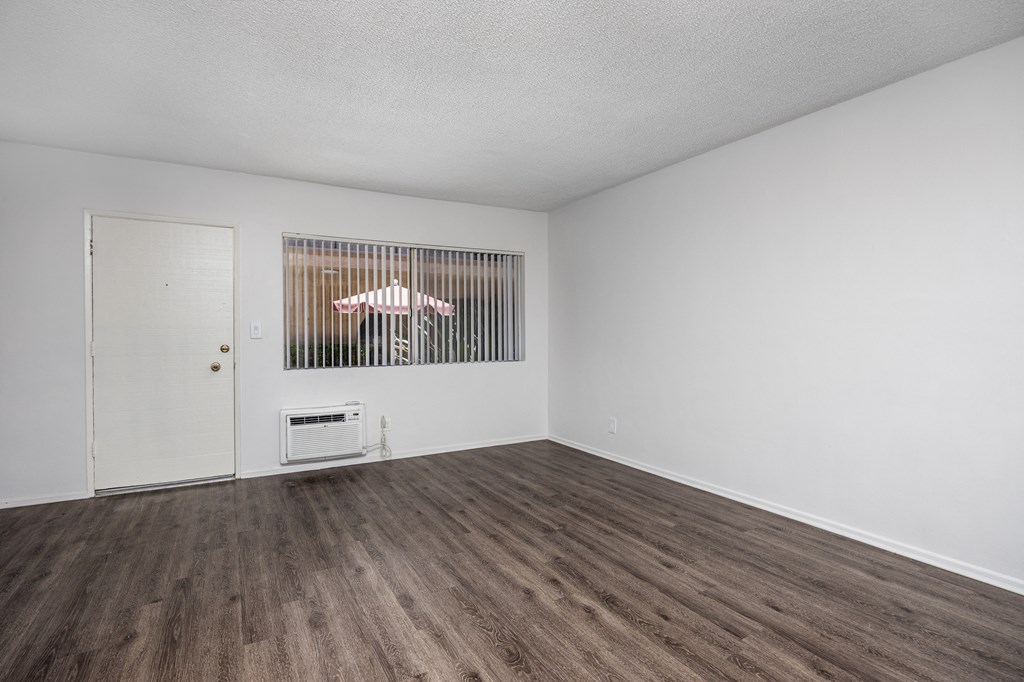 an empty living room with white walls and wood flooring