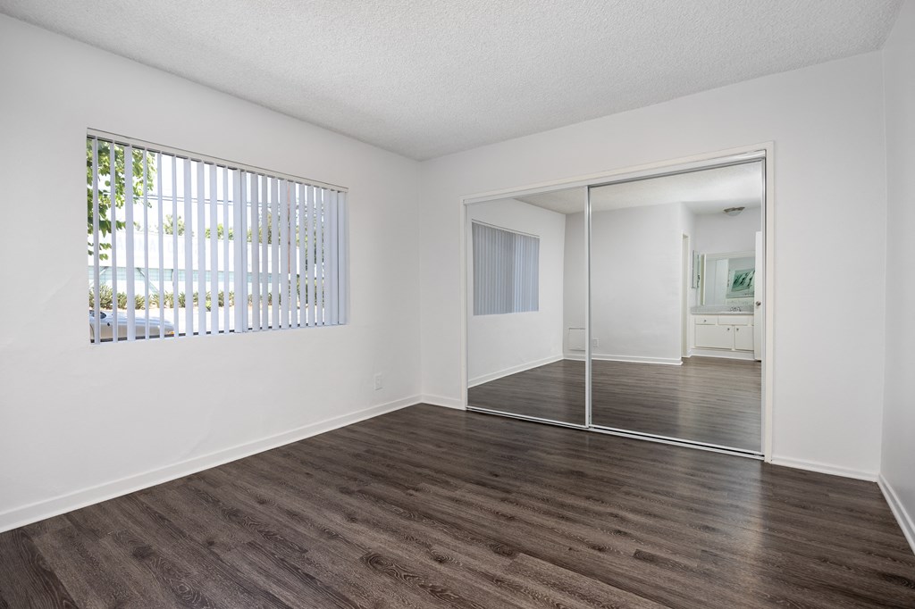 an empty living room with white walls and wood flooring and a sliding glass door