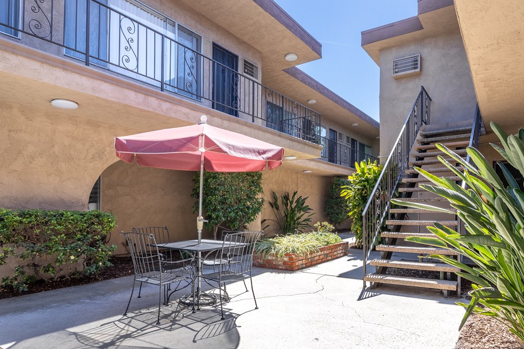 a patio with a table and chairs and an umbrella in front of a building