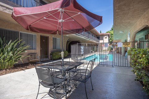 a patio with a table and chairs and a pool in the background