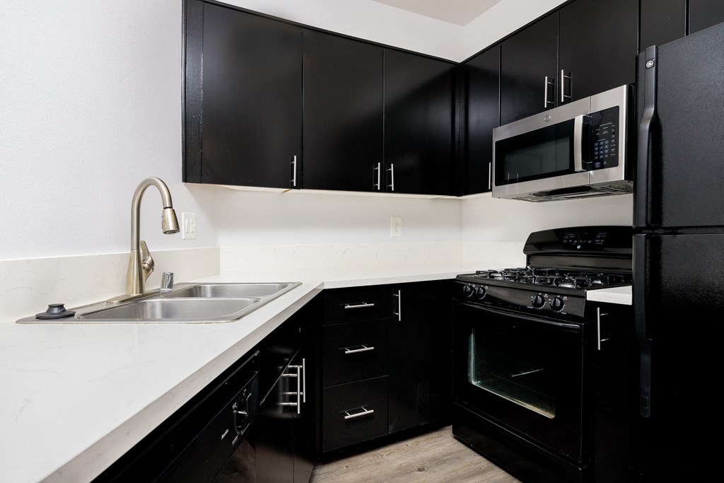 a kitchen with black appliances and white counter tops and black cabinets
