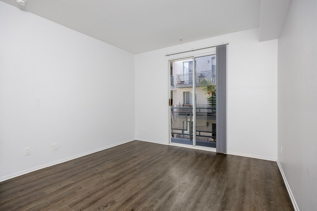 a living room with white walls and a glass door to a balcony