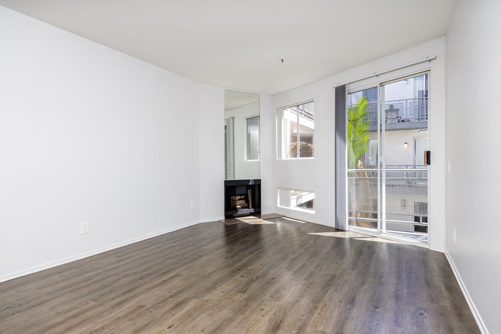 a living room with hardwood floors and a door to a balcony