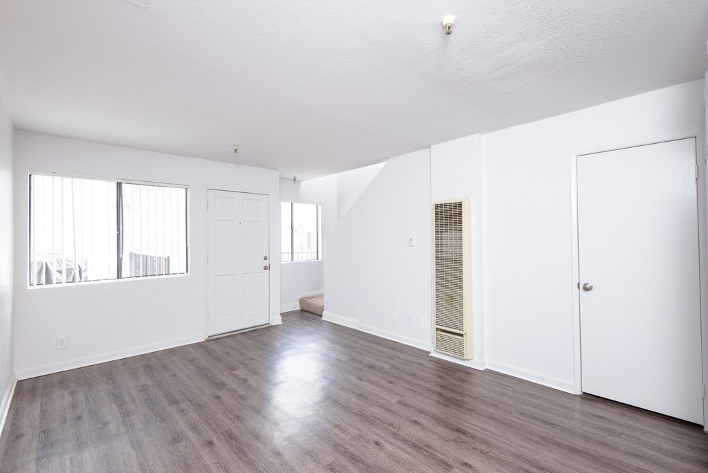 an empty living room with white walls and wood flooring