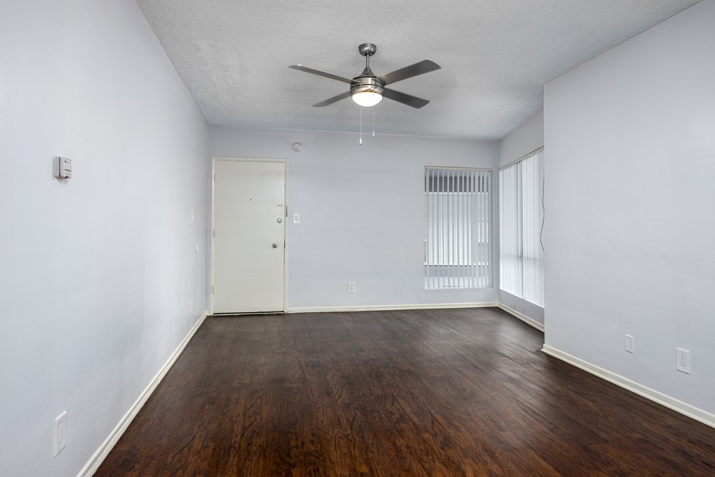 an empty living room with wood flooring and a ceiling fan