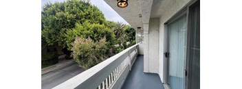 A balcony with a white railing and a glass door.