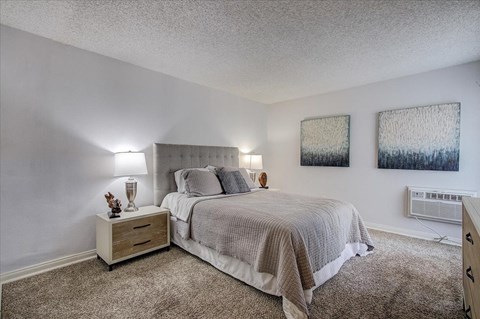 a bedroom with a bed and two paintings on the wall
