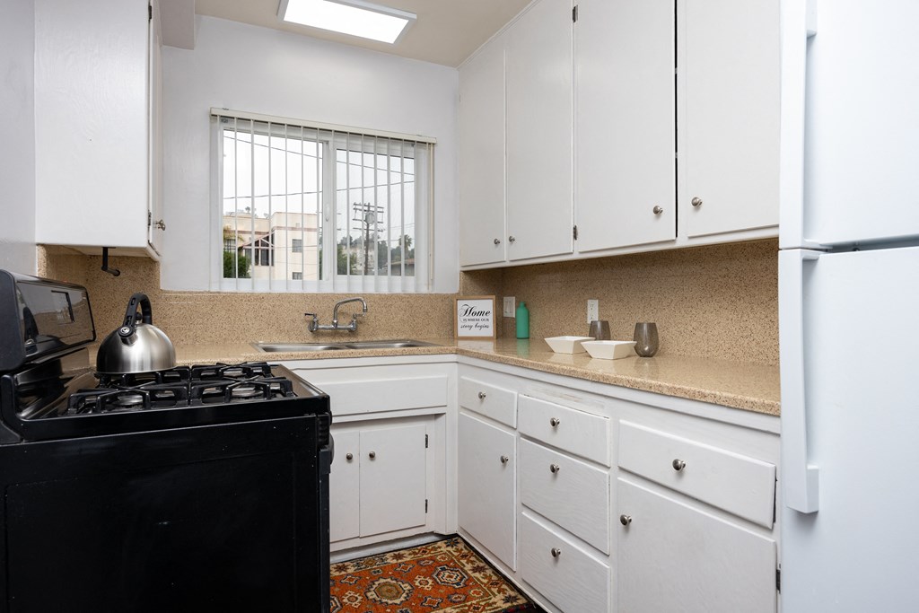a kitchen with white cabinets and a stove and a sink