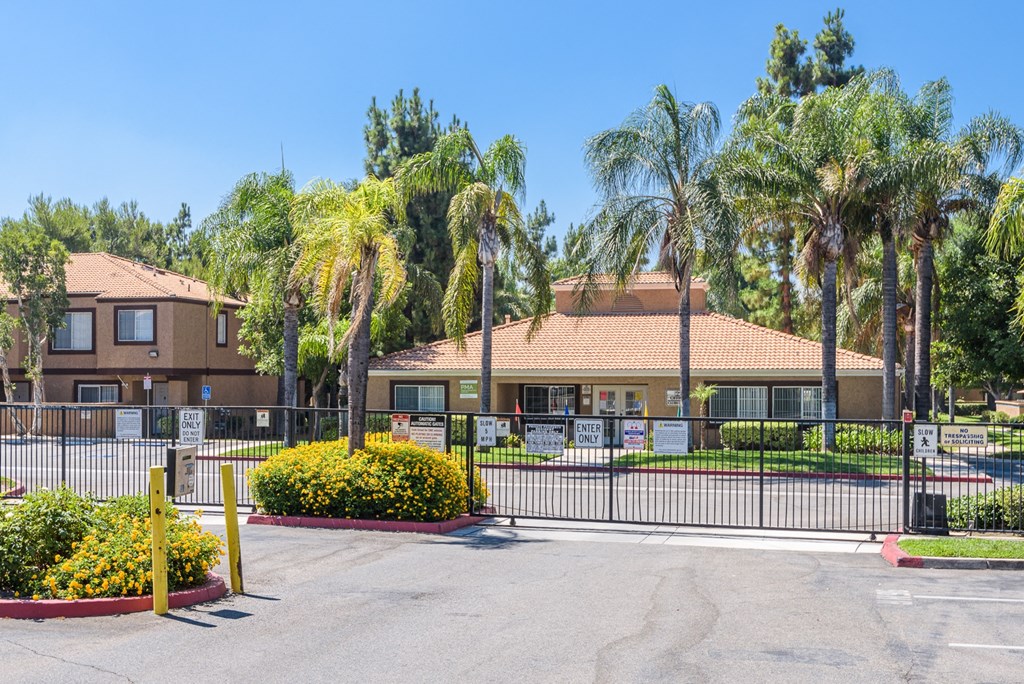 a building with a fence and palm trees in front of it