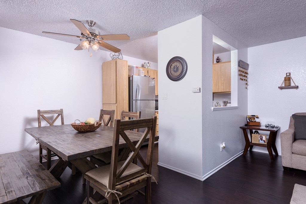 a dining room and living room with a wooden table and a ceiling fan