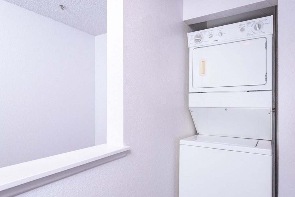 a white washer and dryer in a room with white walls and a window