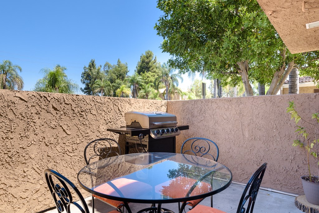 a patio with a table and chairs and a grill
