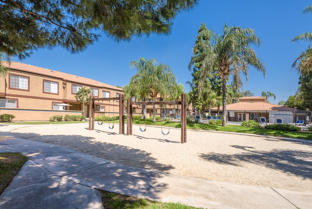 a playground in front of a school with trees and a building
