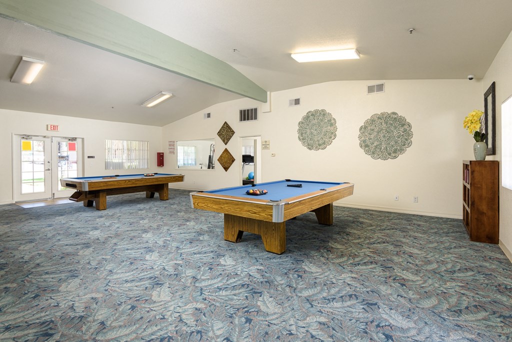 two pool tables in a community room with a blue table