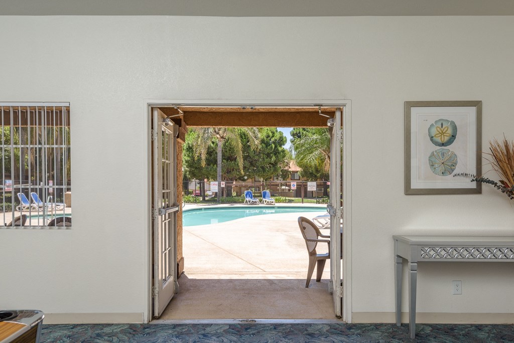 a view of a pool from a living room with a door open to a backyard