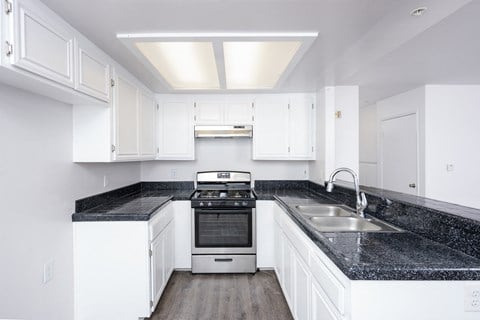 a kitchen with white cabinets and black counter tops and a sink
