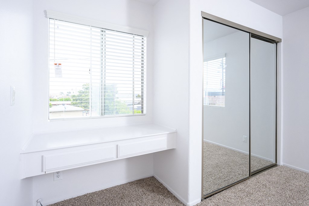an empty room with a window and a mirrored closet